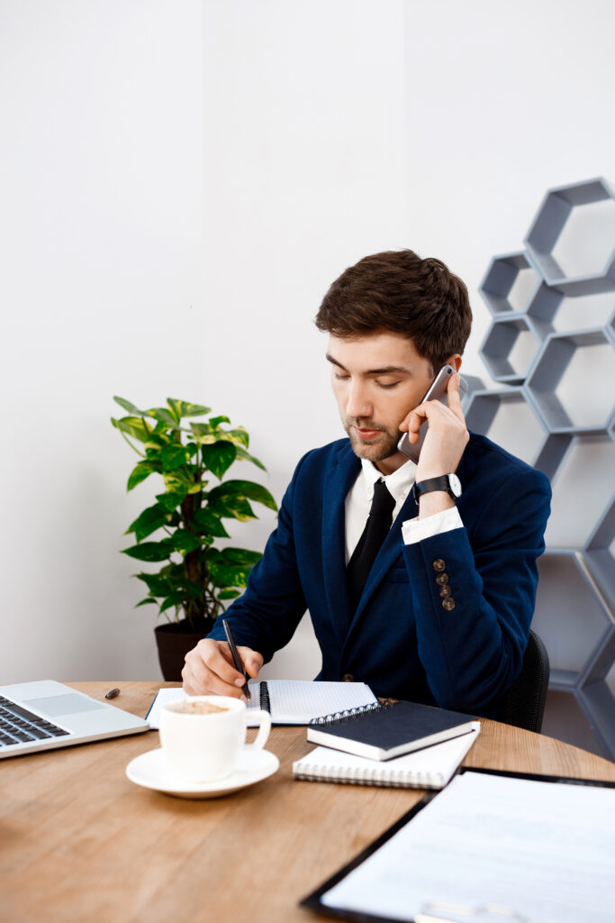 young successful businessman speaking on phone, office background.